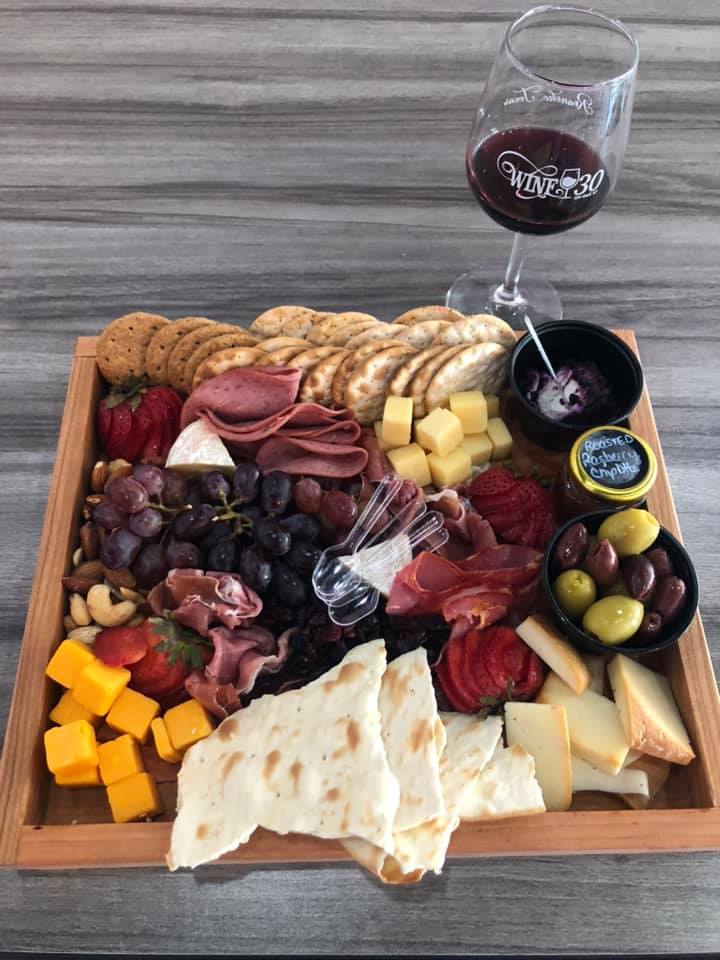 Full charcuterie board with a glass of wine beside it